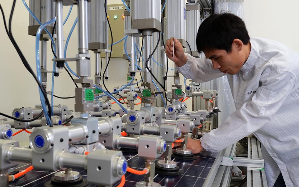 Factory worker with equipment working on solar panel